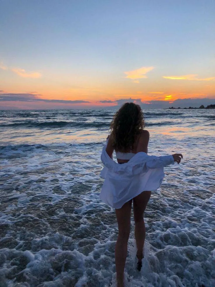 Female Model Walking Into Ocean Waves During Colorful Sunset