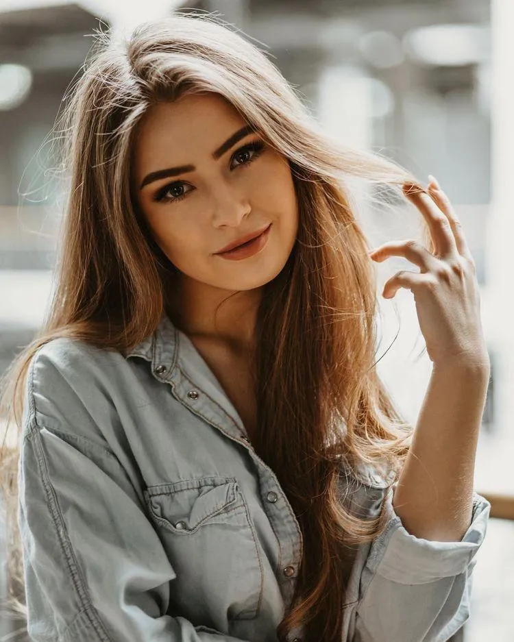 Friendly Model Smiling with Hand in Hair in Soft Lighting