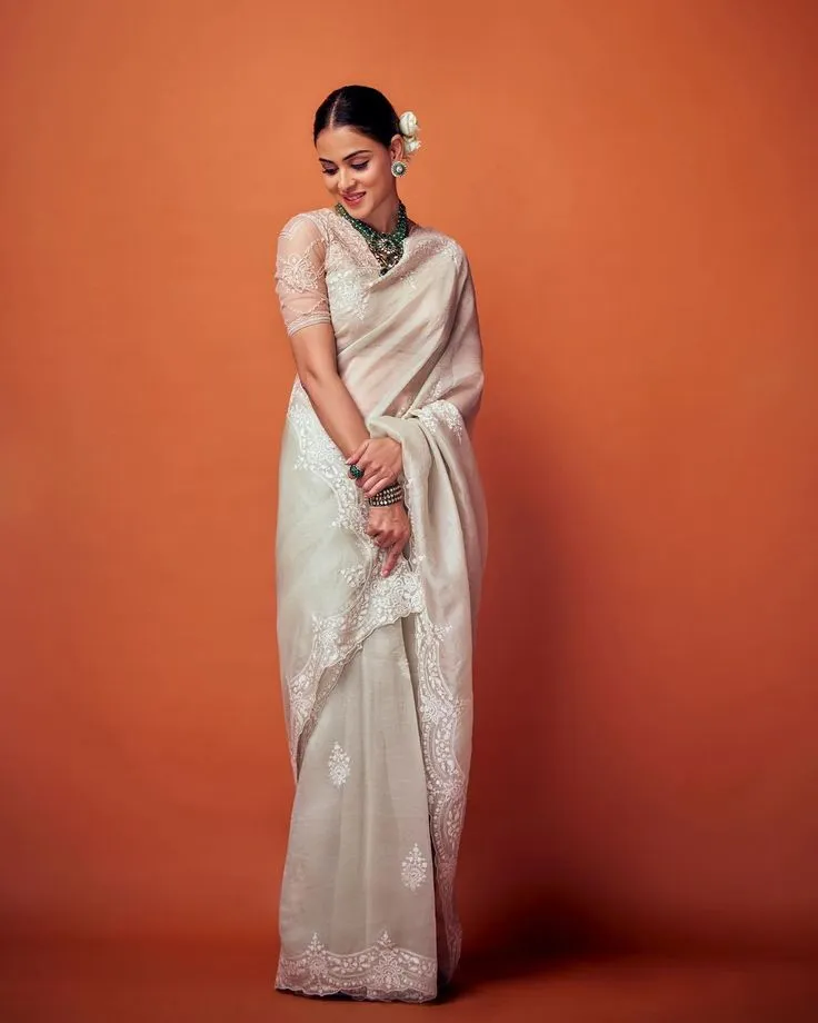 Genelia in a Kerala saree standing near the orange backdrop
