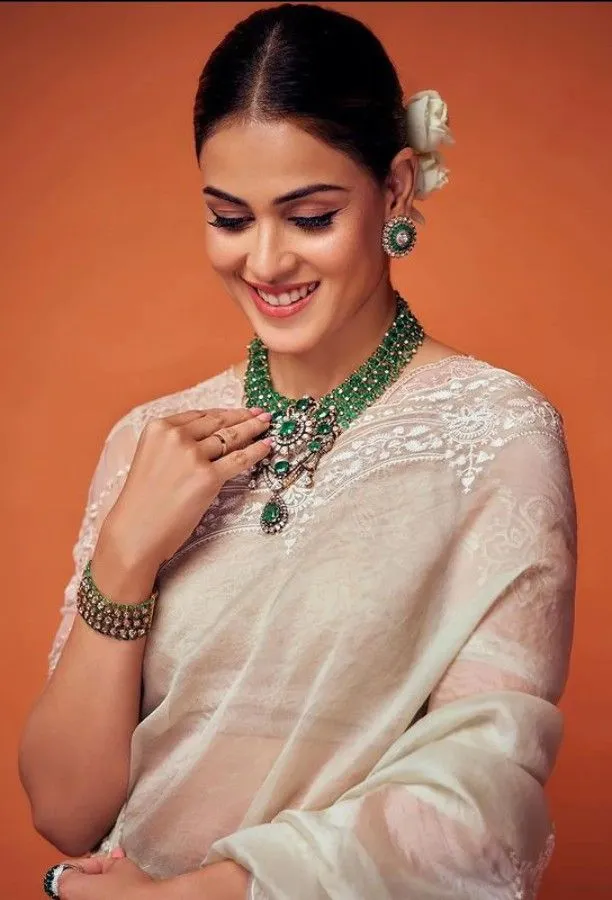Genelia looking down wearing a white saree and a cute smile