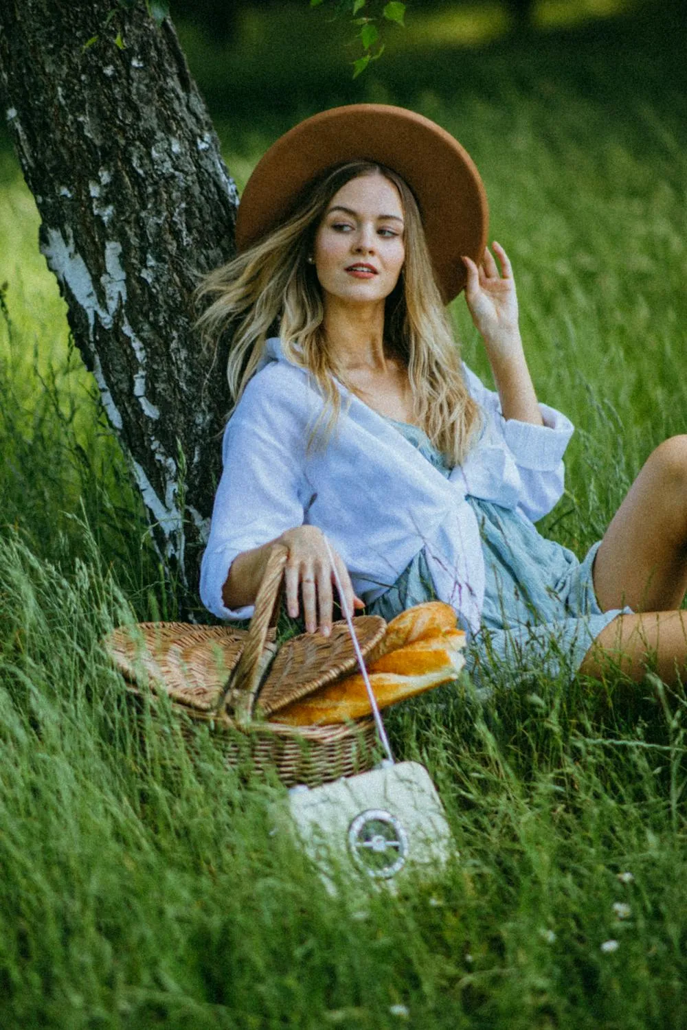 Girl in a Hat Is Enjoying a Picnic in a Green Grassy Field