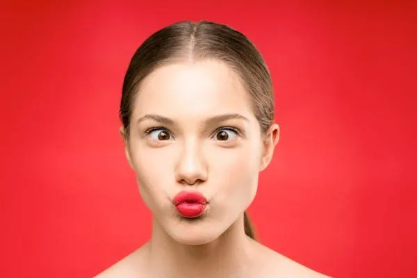 Girl Making a Funny Surprised Face in Front of a Red Wall