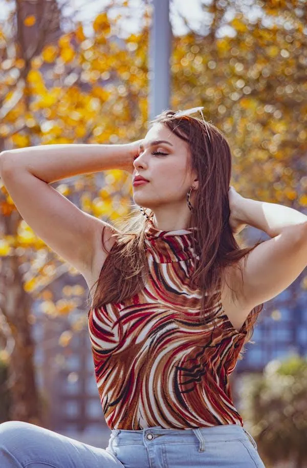 Girl in Printed Top Posing with Hand on Her Head in the Fall