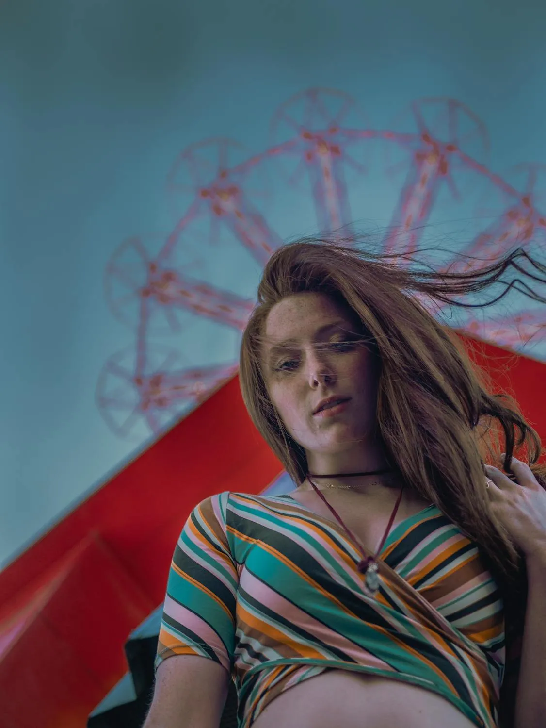 Girl Standing Near the Ferris Wheel with Wind in Her Hair