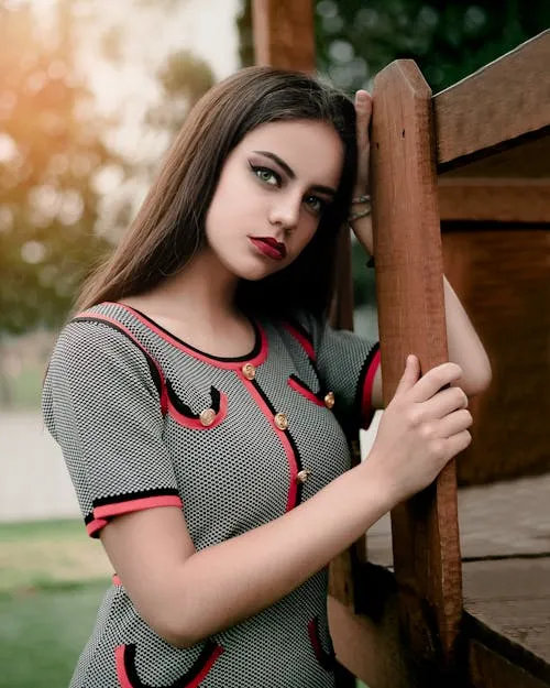 Graceful Woman in a Grey Dress Standing by a Wooden Fence