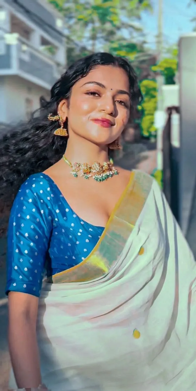 Hansika Krishna in a white and blue saree standing outdoors