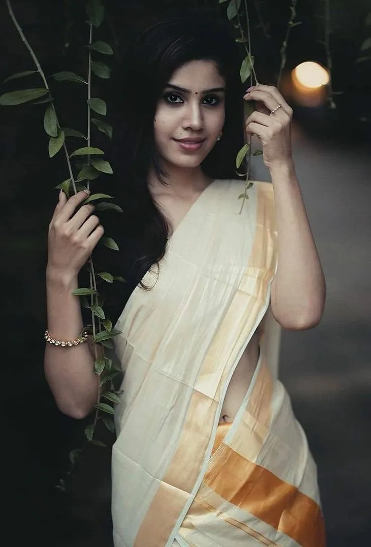 Hot image of a woman in an Onam saree holding green leaves