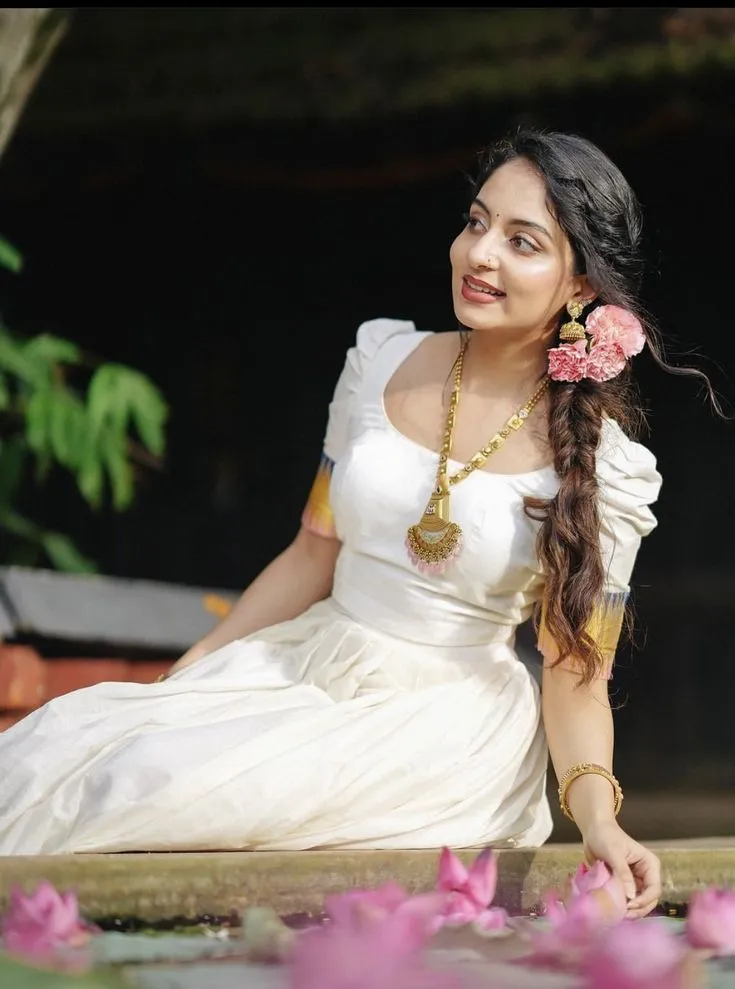 Ishaani Krishna in a Kerala dress sitting near the water