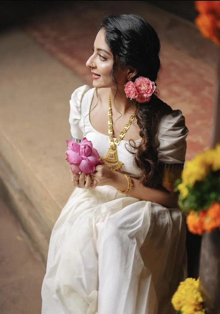 Ishaani Krishna in a white dress holding a pink flower image
