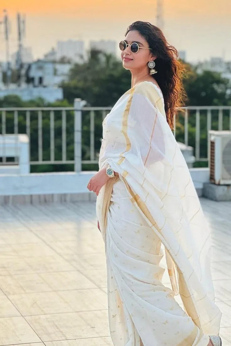 Keerthy Suresh in a Kerala saree with a cooling glass image