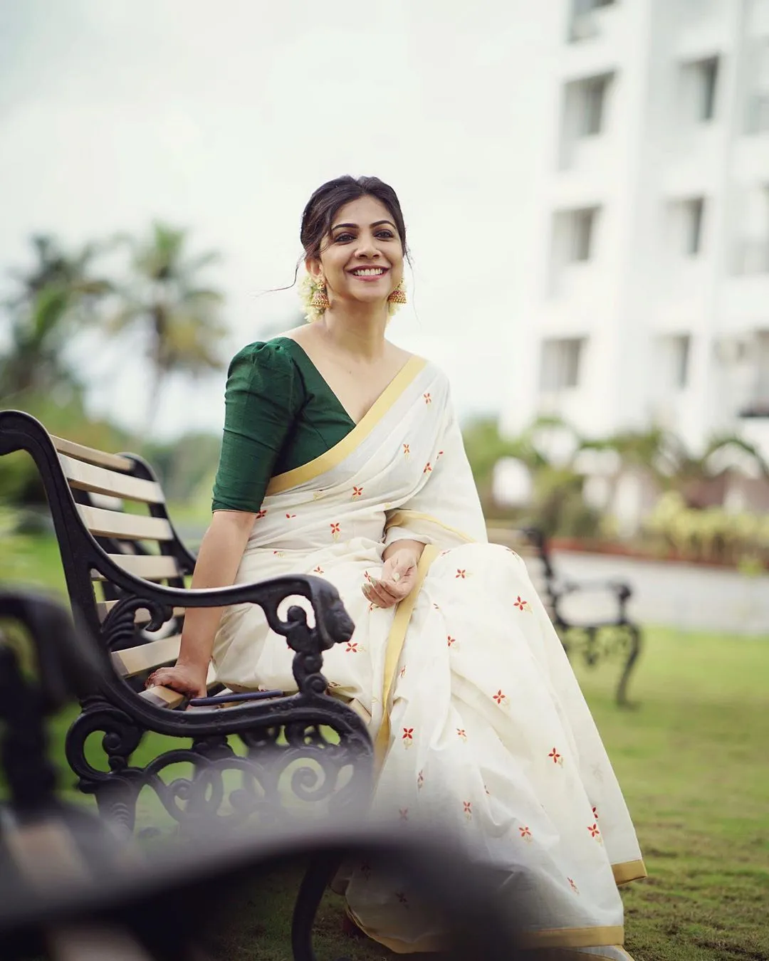 Madonna Sebastian in a Kerala kasavu saree sitting outdoors