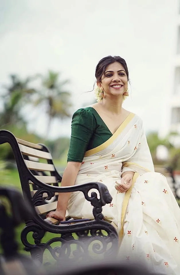 Madonna Sebastian sitting on a park bench wearing a saree