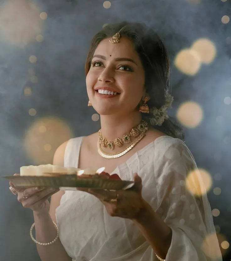 Mahima Nambiar in a white saree holding a golden plate image