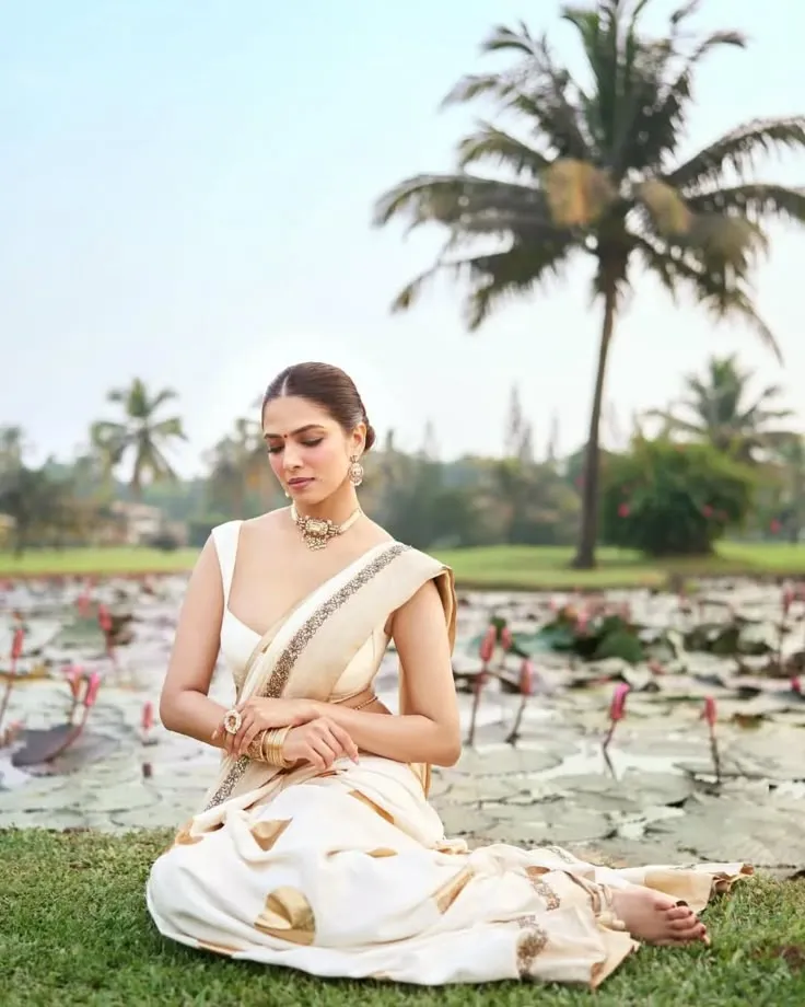 Malavika Mohanan sitting in a pond with a lily flower image