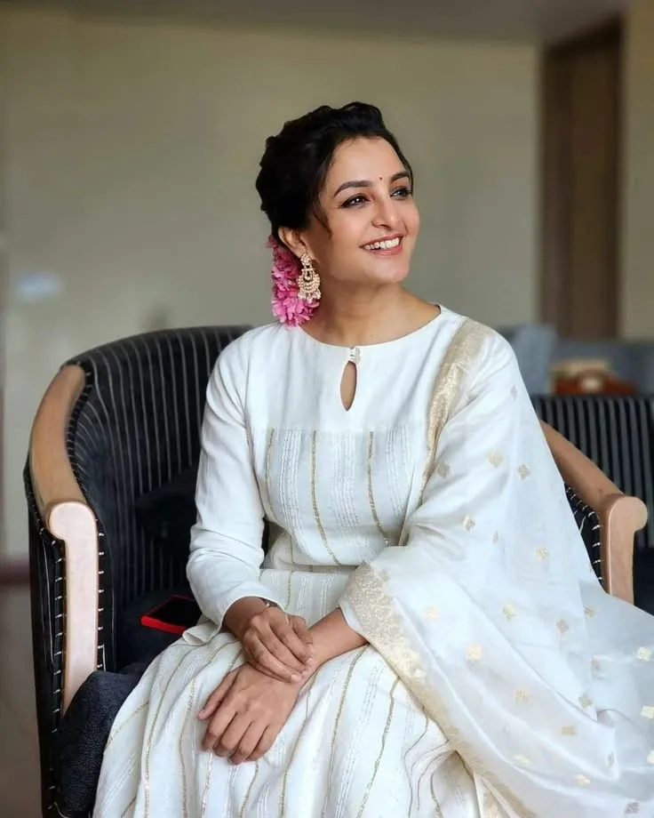 Manju Warrier in a white outfit and sitting on a chair image