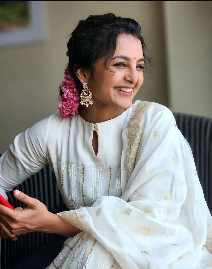 Manju Warrier sitting on the chair wearing a white dress