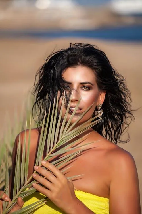 Model Holding Plants Posing Under the Sunlight Near Ocean