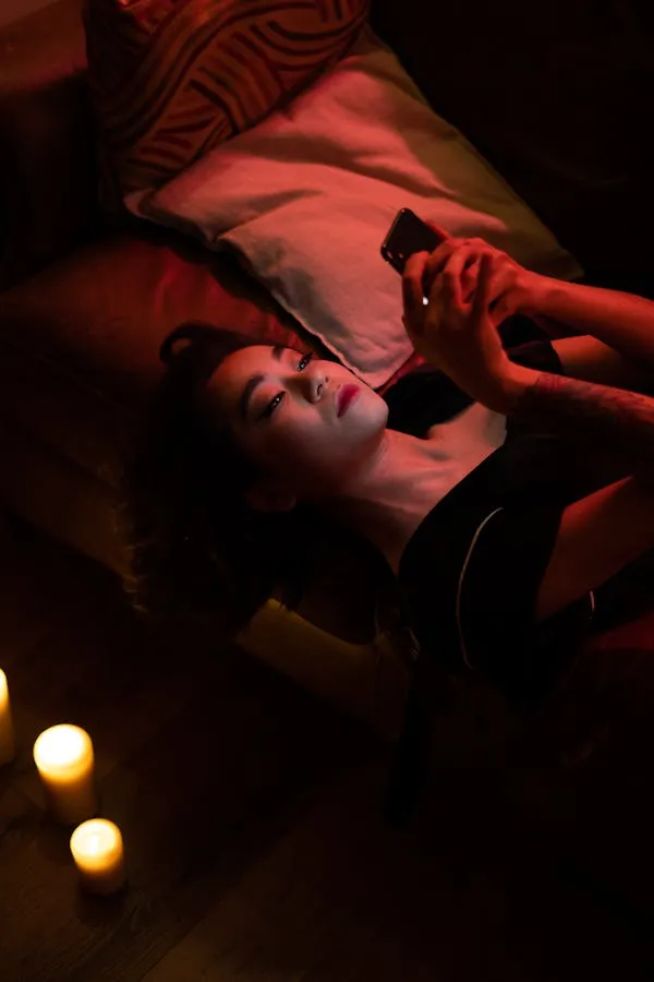Moody Photo of a Woman Lying on a Bed and Watching Her Phone