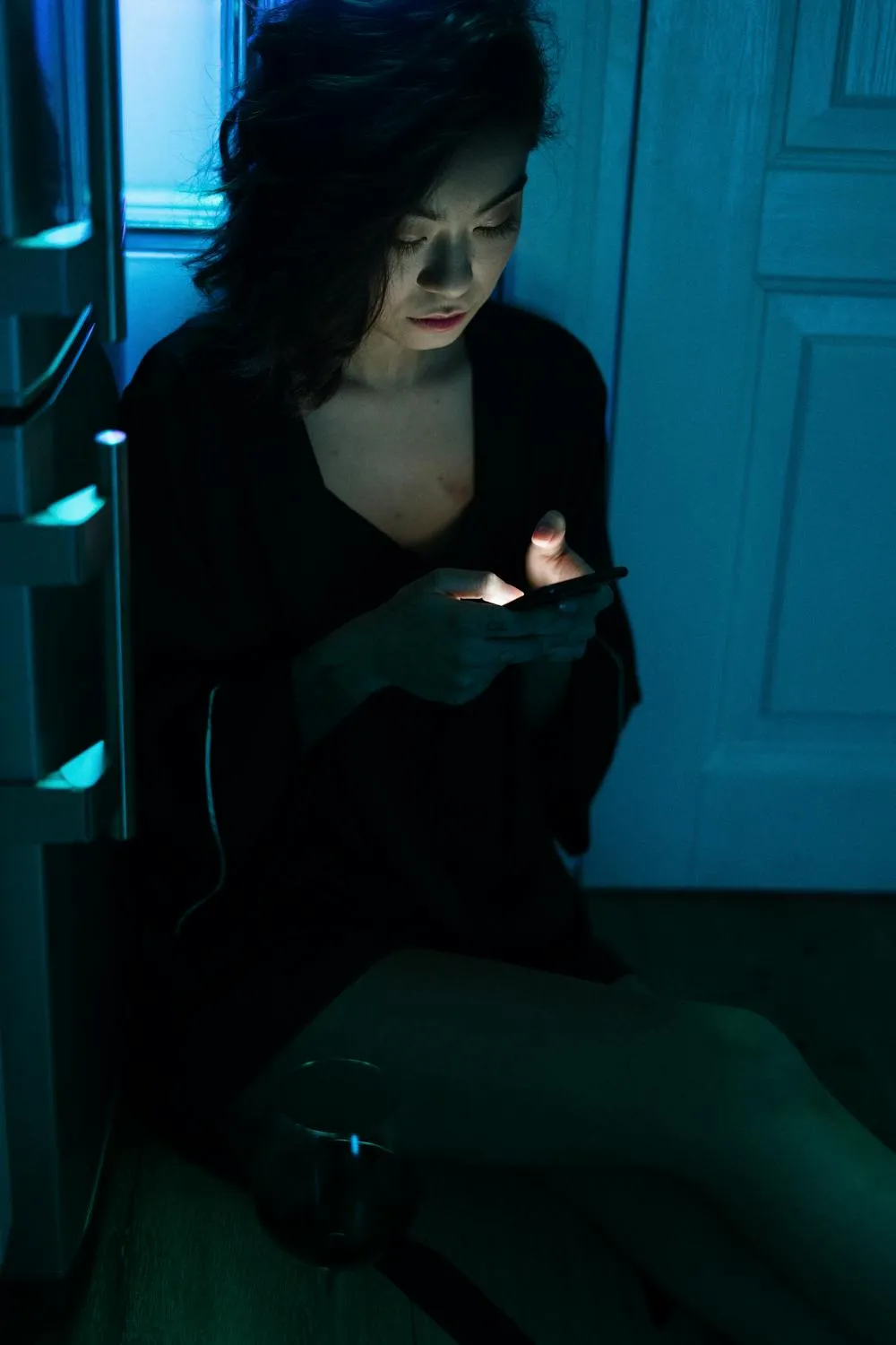 Moody Photo of a Woman Sitting in a Dimly Lit Blue Room
