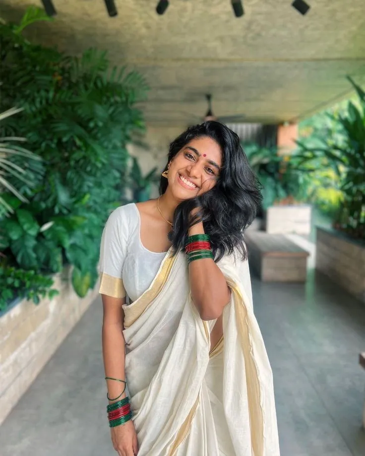 Nimisha Sajayan in kasavu saree standing in green background