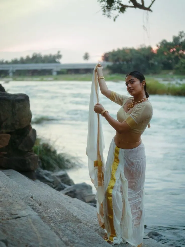Payal Radhakrishna in a Kerala saree standing near the river