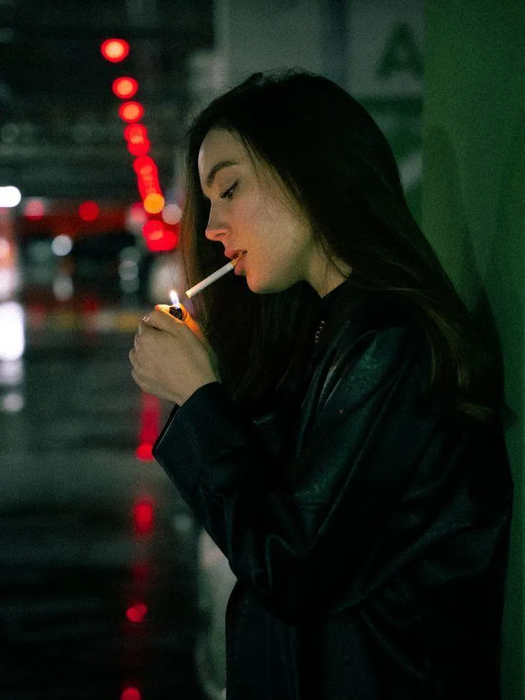 Pensive Woman in a Black Jacket with Blurred City Lights