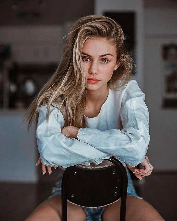 Pensive Woman Sitting Indoors in a Light Blue Sweatshirt