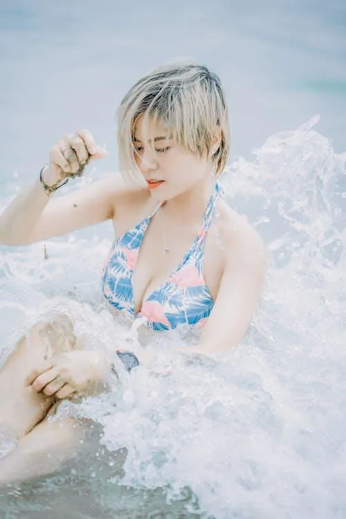 Playful Woman Splashing Water While Wearing a Swimsuit Image