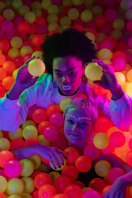 Playful Women Having Fun Inside a Colorful Ball Pit Hd Image