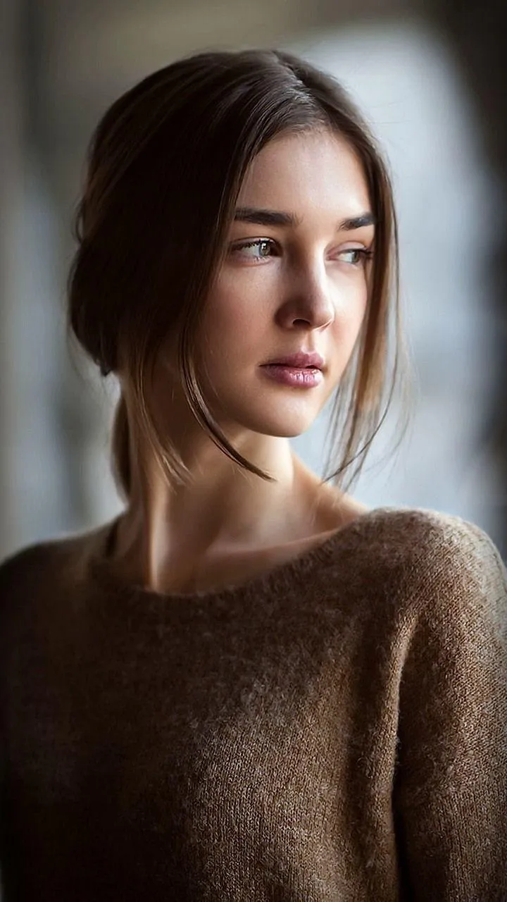 Portrait of a Brunette Woman in a Brown Sweater by a Window