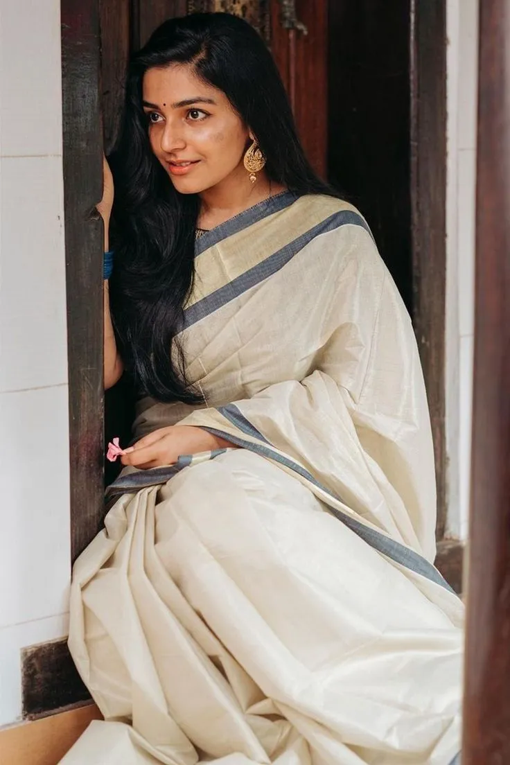 Rajisha Vijayan in a neriyal saree sitting near the door