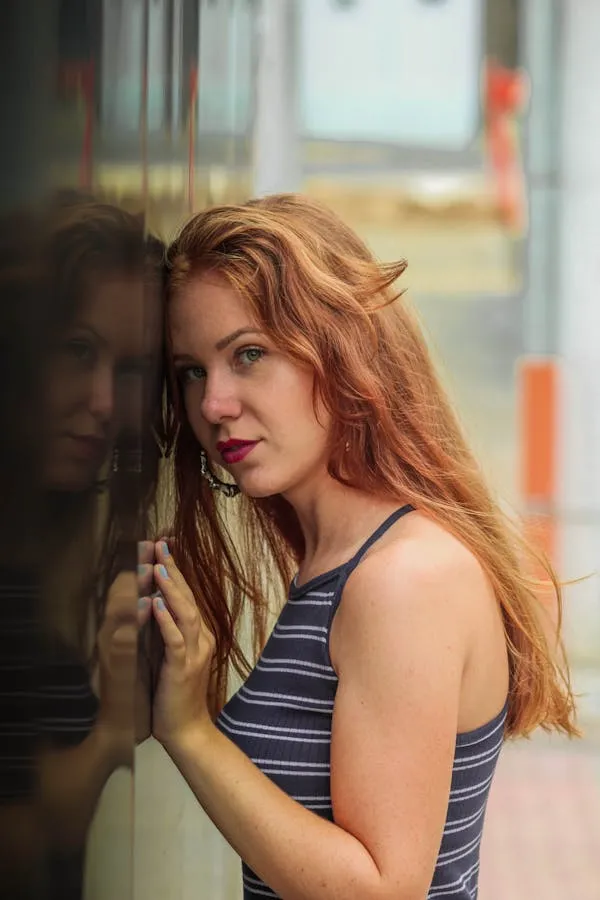Red Haired Woman Gazing Into the Mirror with a Serious Look