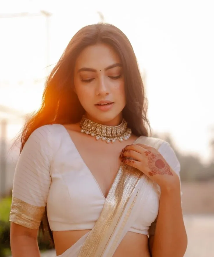 Reem Shaikh in a Kasavu saree standing under the sunset