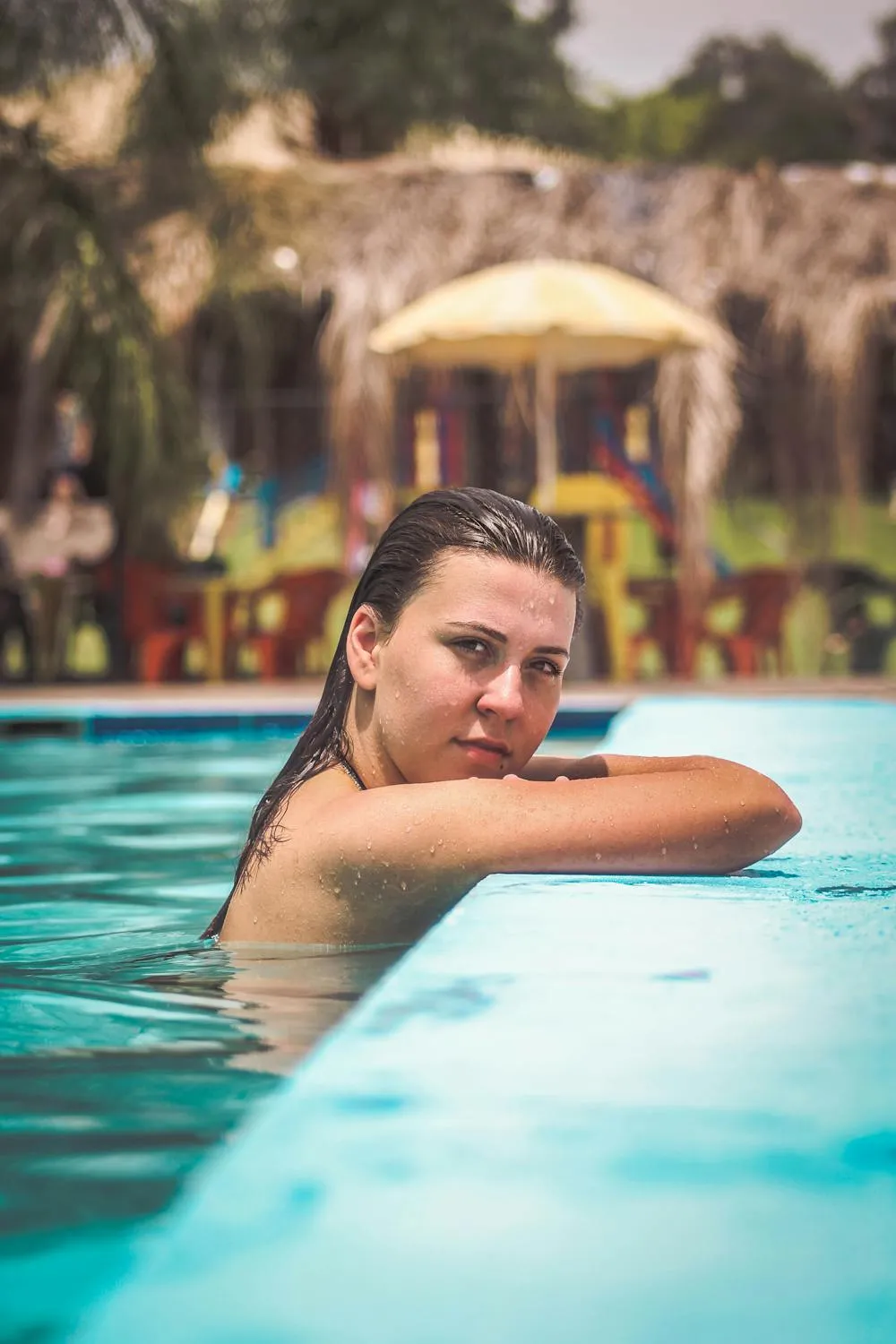 Relaxed Woman Resting in a Blue Pool with Palm Trees View