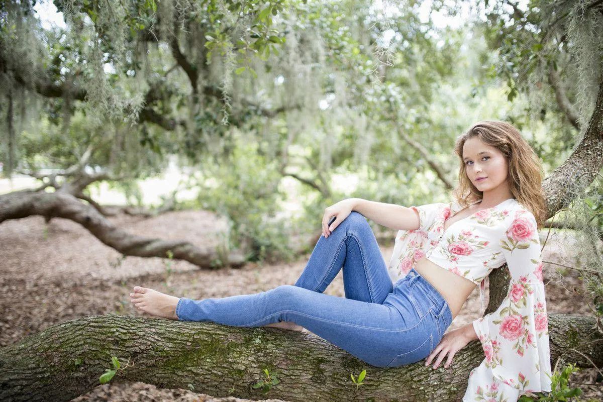 Relaxed Woman Resting Outdoors on a Tree Branch Smiling