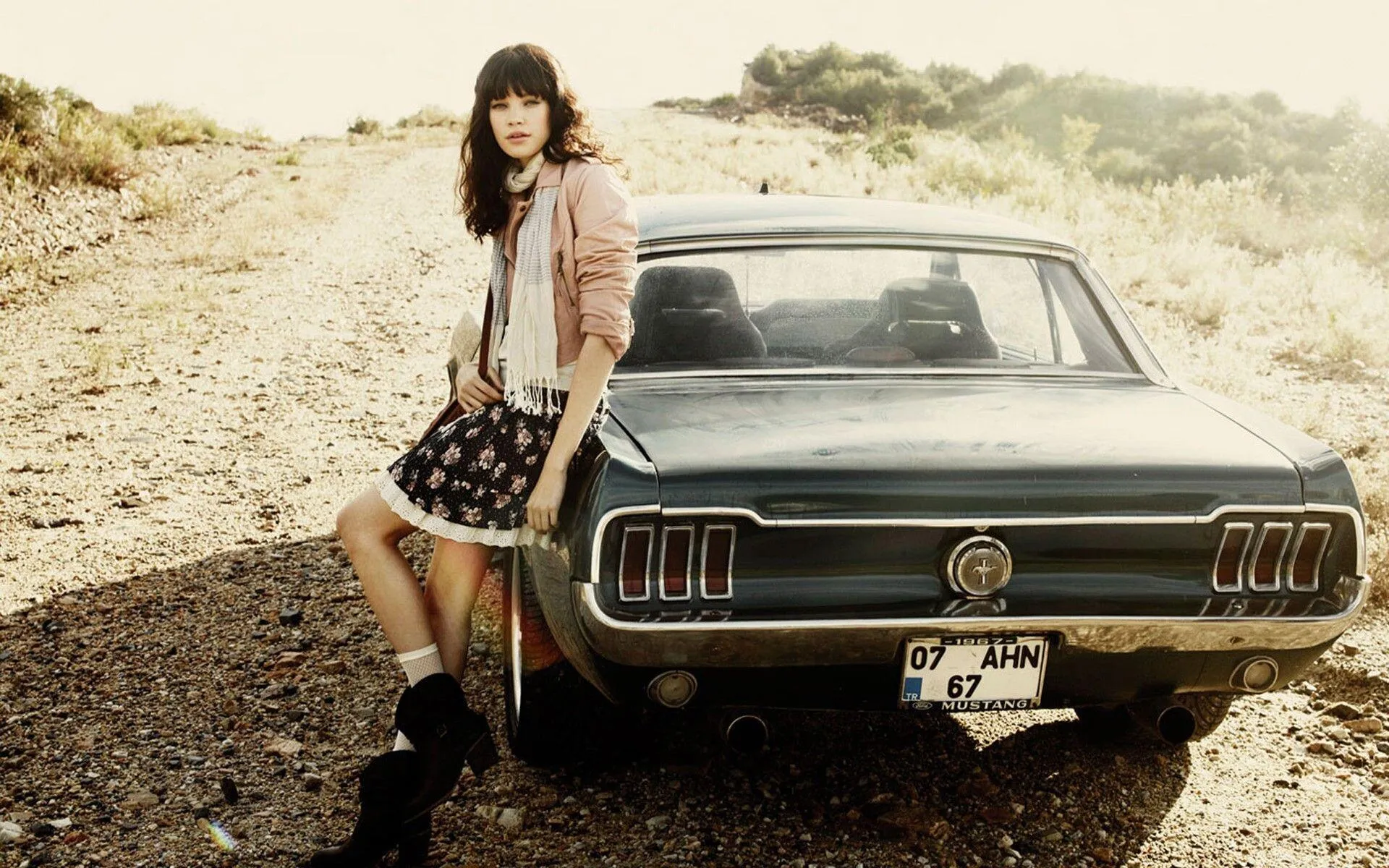 Retro Style Woman Leaning on a Classic Car in the Sunlight