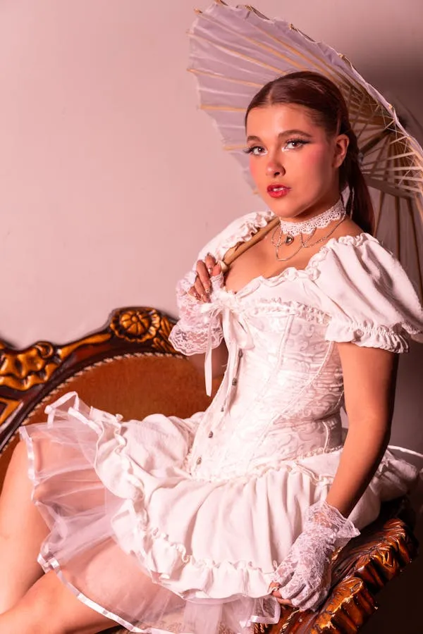 Retro Styled Model in a White Dress Sitting on Vintage Chair