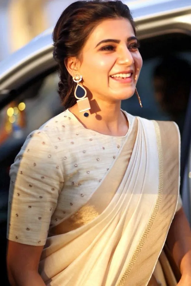 Samantha in a white saree near a car with a cute smile image