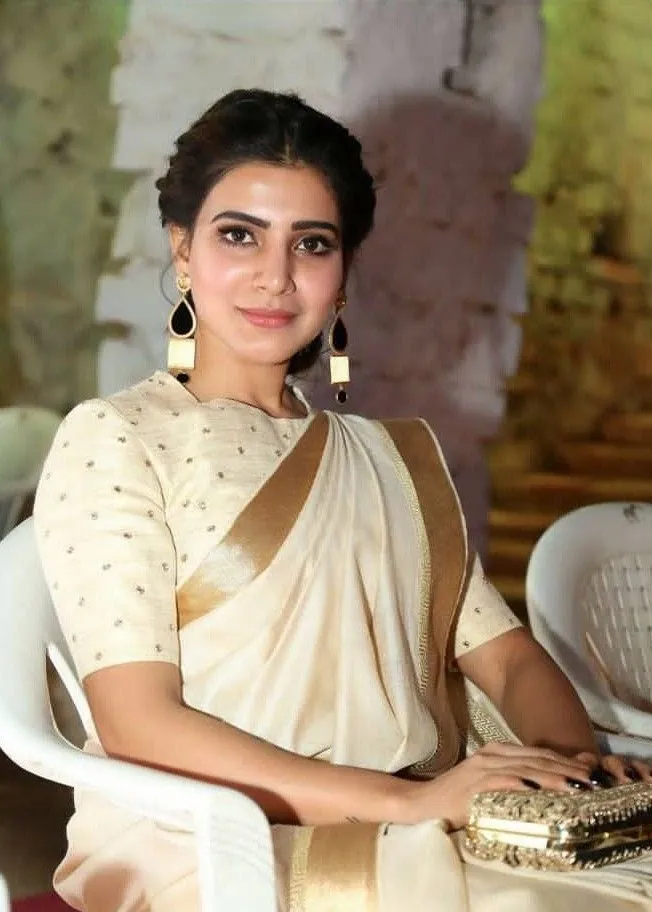 Samantha in a white saree sitting in a white chair wallpaper