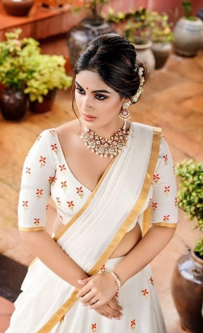 Samyuktha in a neriyal saree sitting near the green plants