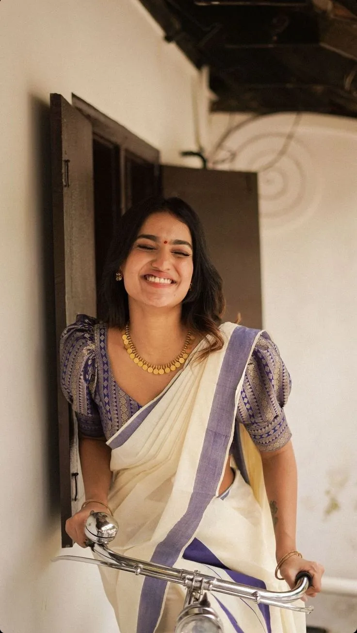 Saniya Iyappan with eyes closed smiles sitting in a cycle