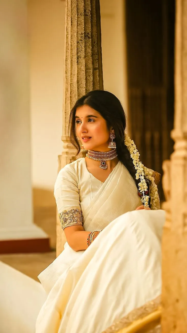 Sanjana Sarathy leaning on the pillar wearing an Onam saree