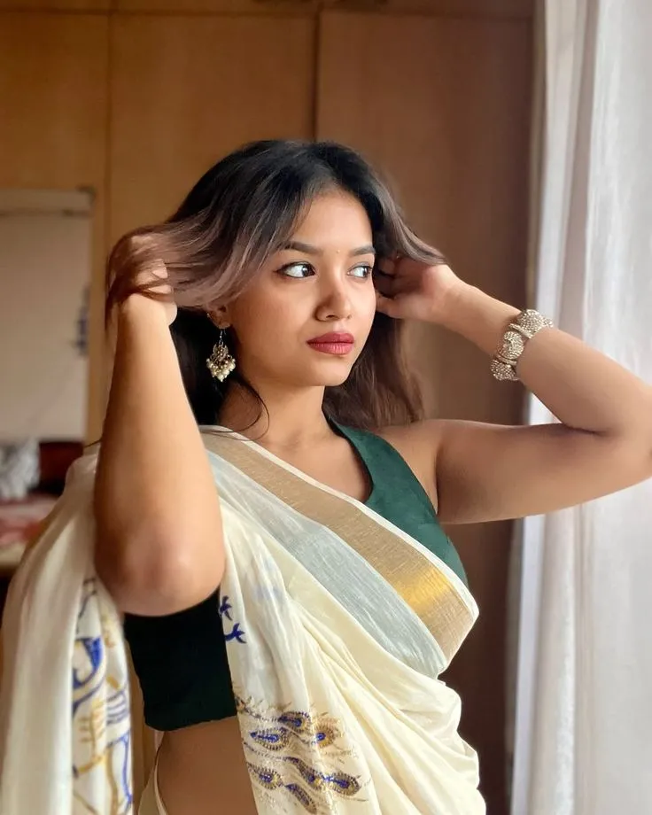Sanjana Tiwari in a Kasavu saree with her hand on her hair