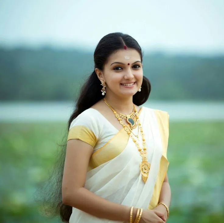 Saranya Mohan in a Kerala saree standing near the water