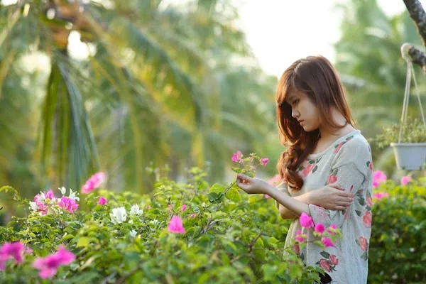 Serene Woman in a Floral Dress Using Her Phone in a Garden