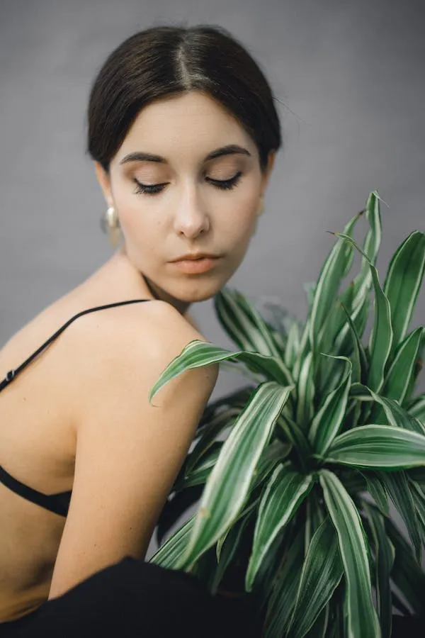 Serene Woman Holding Green Plant in Natural Indoor Setting