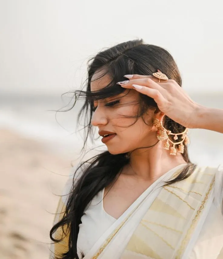 Shwetha Poornima in a Kerala saree with hand on her hair