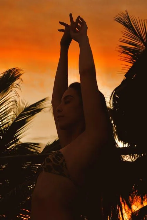 Silhouette of a Woman Dancing At Sunset with Palm Trees
