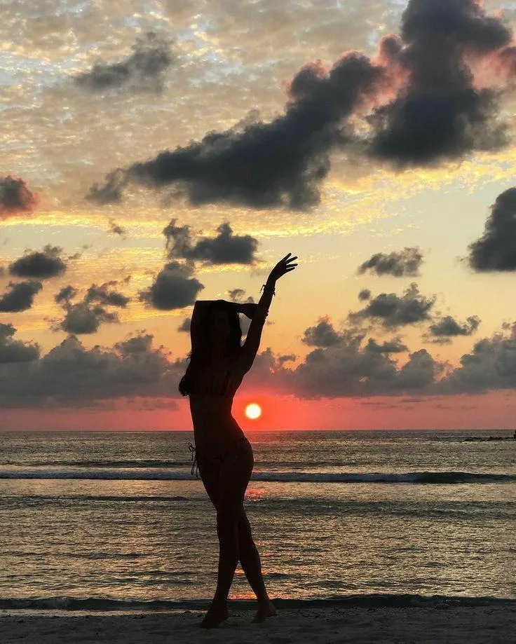 Silhouette of a Woman Jumping At Sunset by the Sea Wallpaper