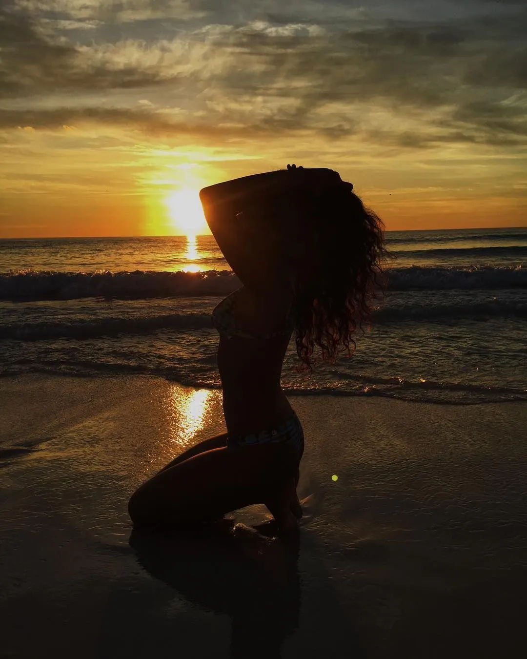 Silhouette of a Woman Kneeling on the Beach At Sunset Image